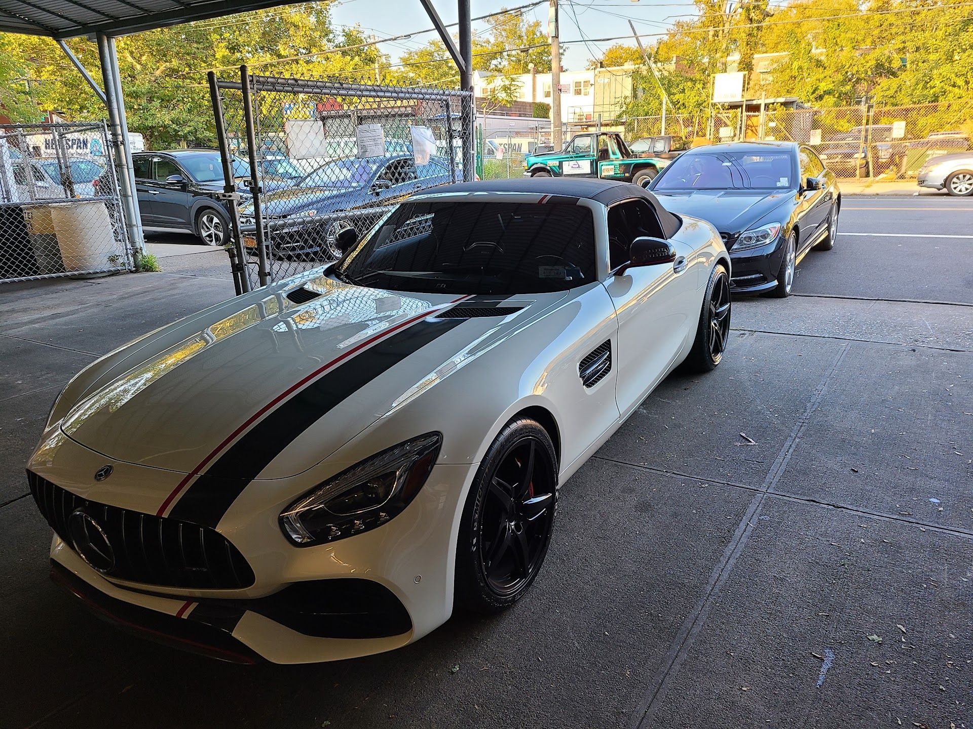 White Mercedes sports car with black stripes parked in front of a car wash.