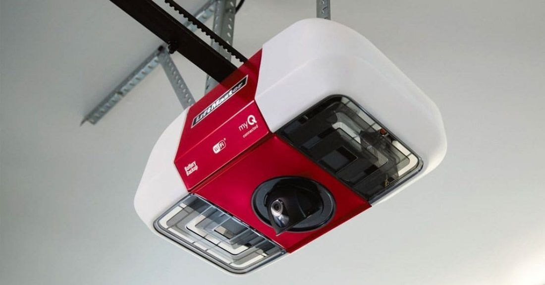 A white and red smart garage door opener with a built-in camera, mounted to a garage ceiling.