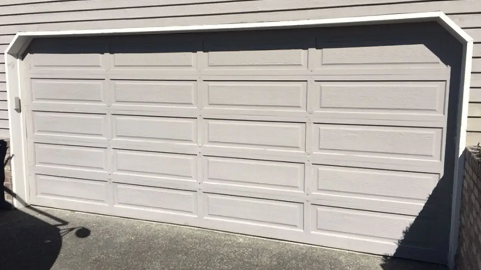 A beige, rectangular residential garage door with a paneled design, installed in a home exterior wall.