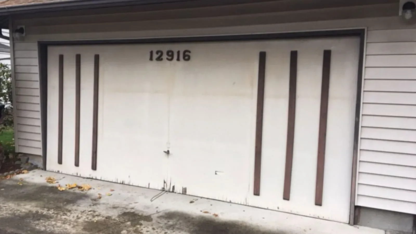 A white garage door featuring dark brown vertical decorative slats and the number 12916 near the top.
