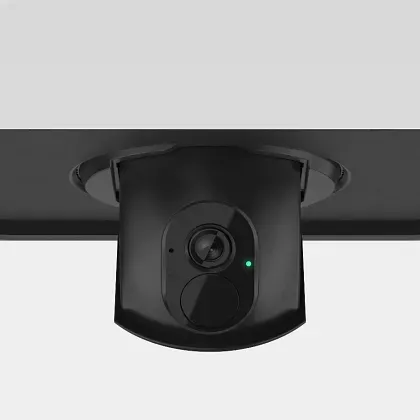 A black security camera mounted to a ceiling, featuring a lens and a small, illuminated green status light.