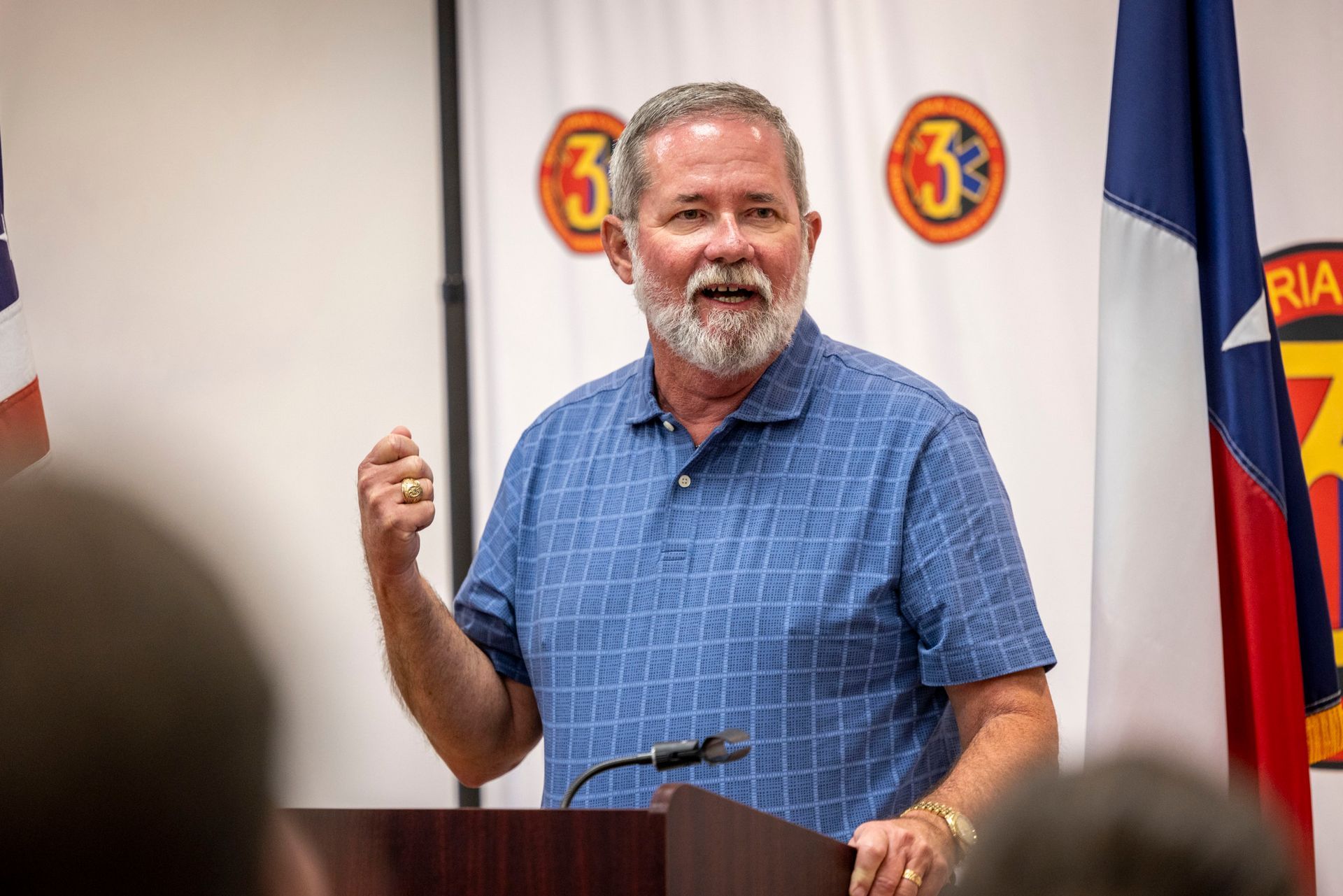 A man with a beard is standing at a podium giving a speech.