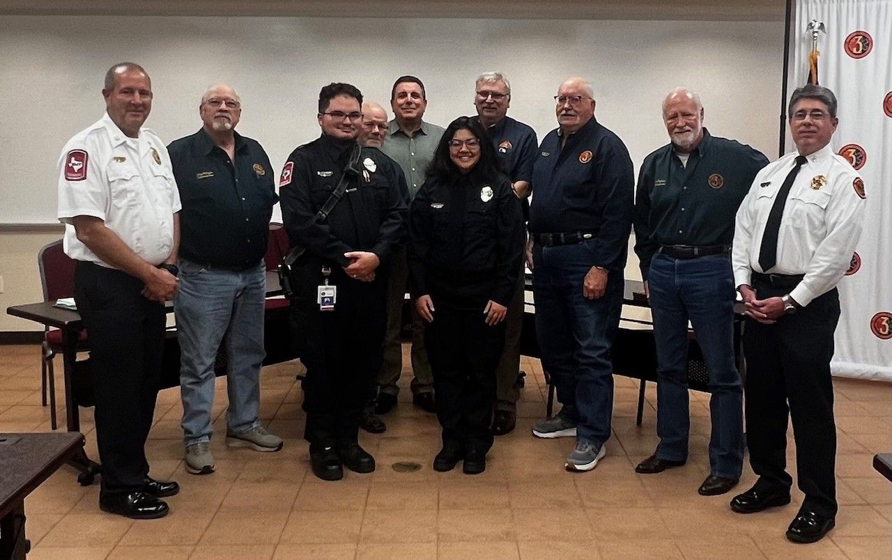 A group of individuals in uniform and professional attire posing together in a meeting room.
