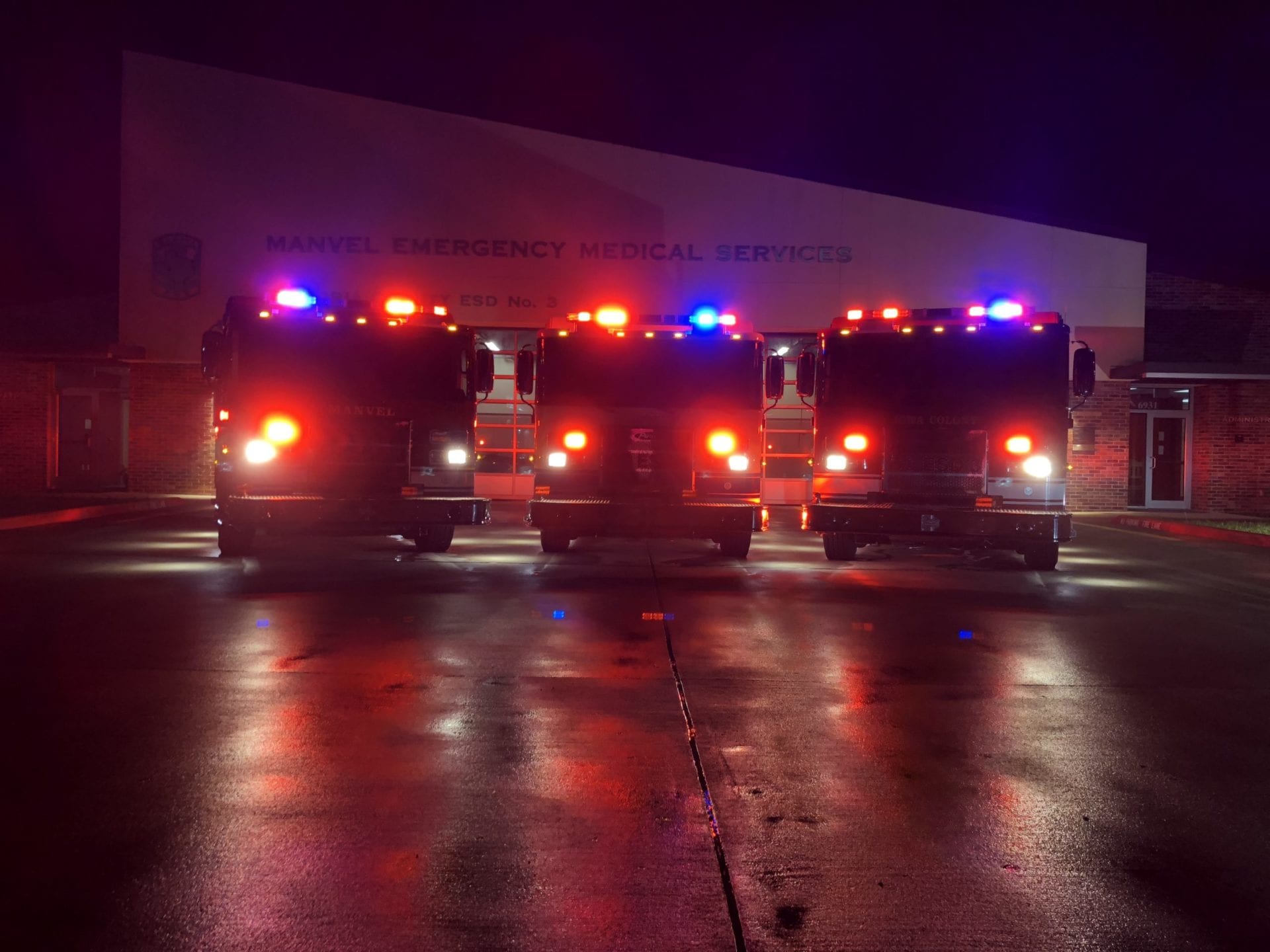 A row of fire trucks are parked in front of a building that says emergency medical services