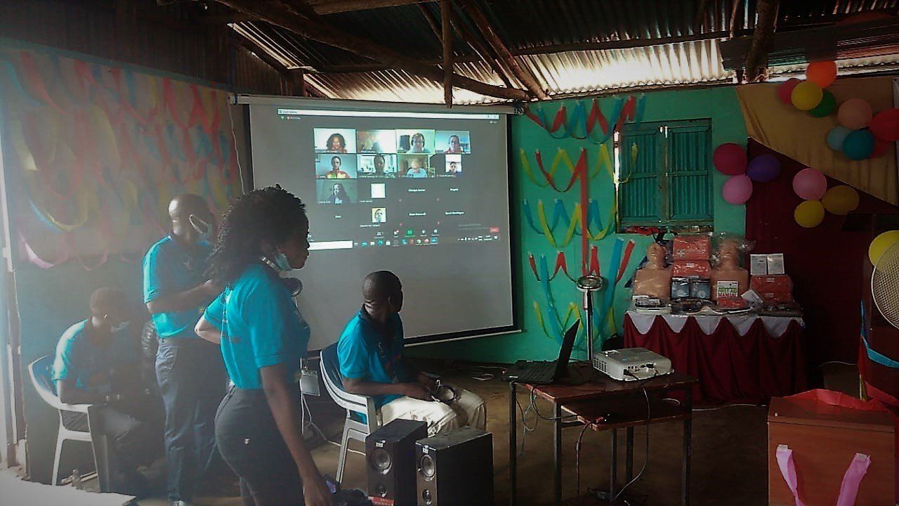 A group of people are standing around a projector screen in a room.