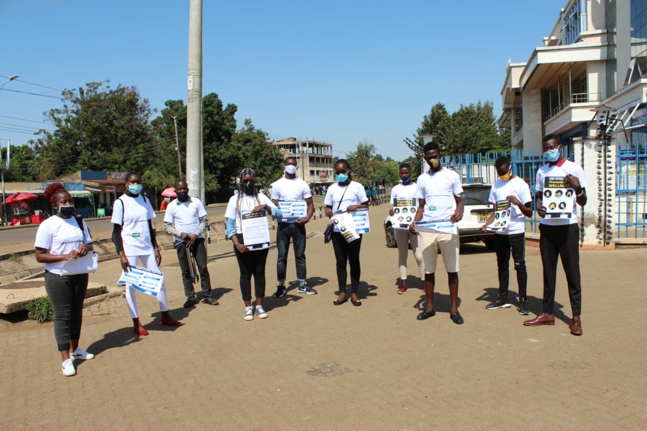 A group of people wearing masks are standing on a street