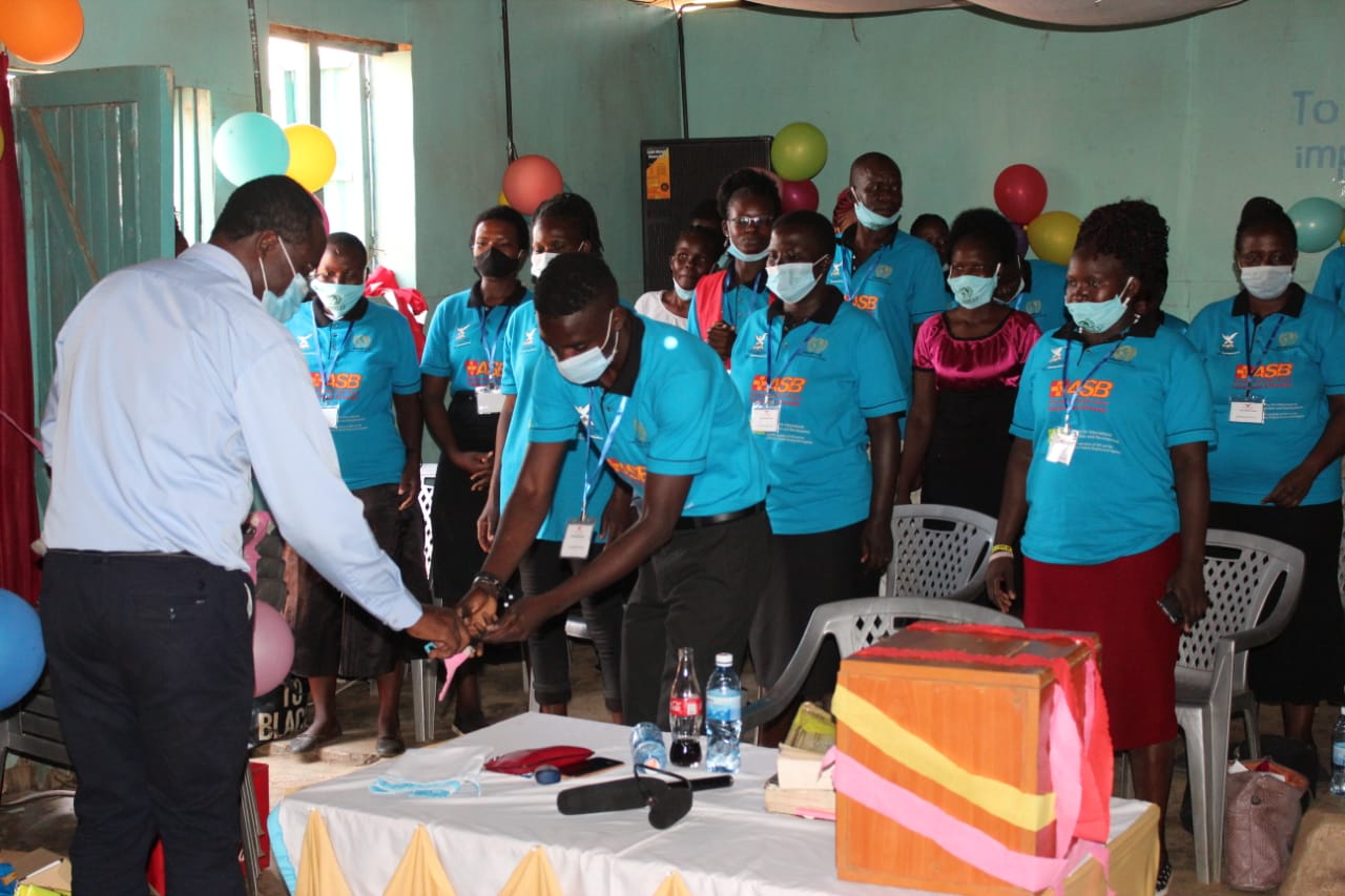 A group of people wearing masks are standing around a table.