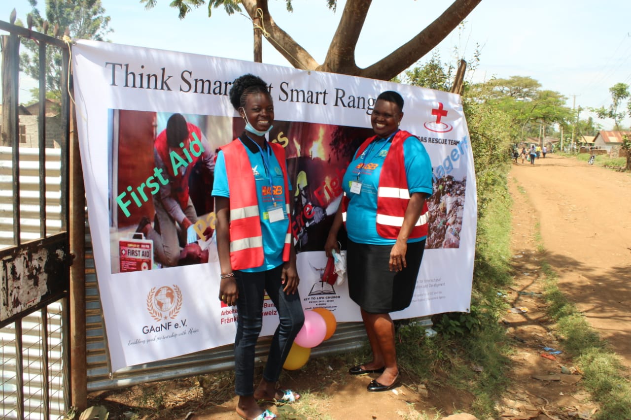 Two women standing in front of a sign that says first aid