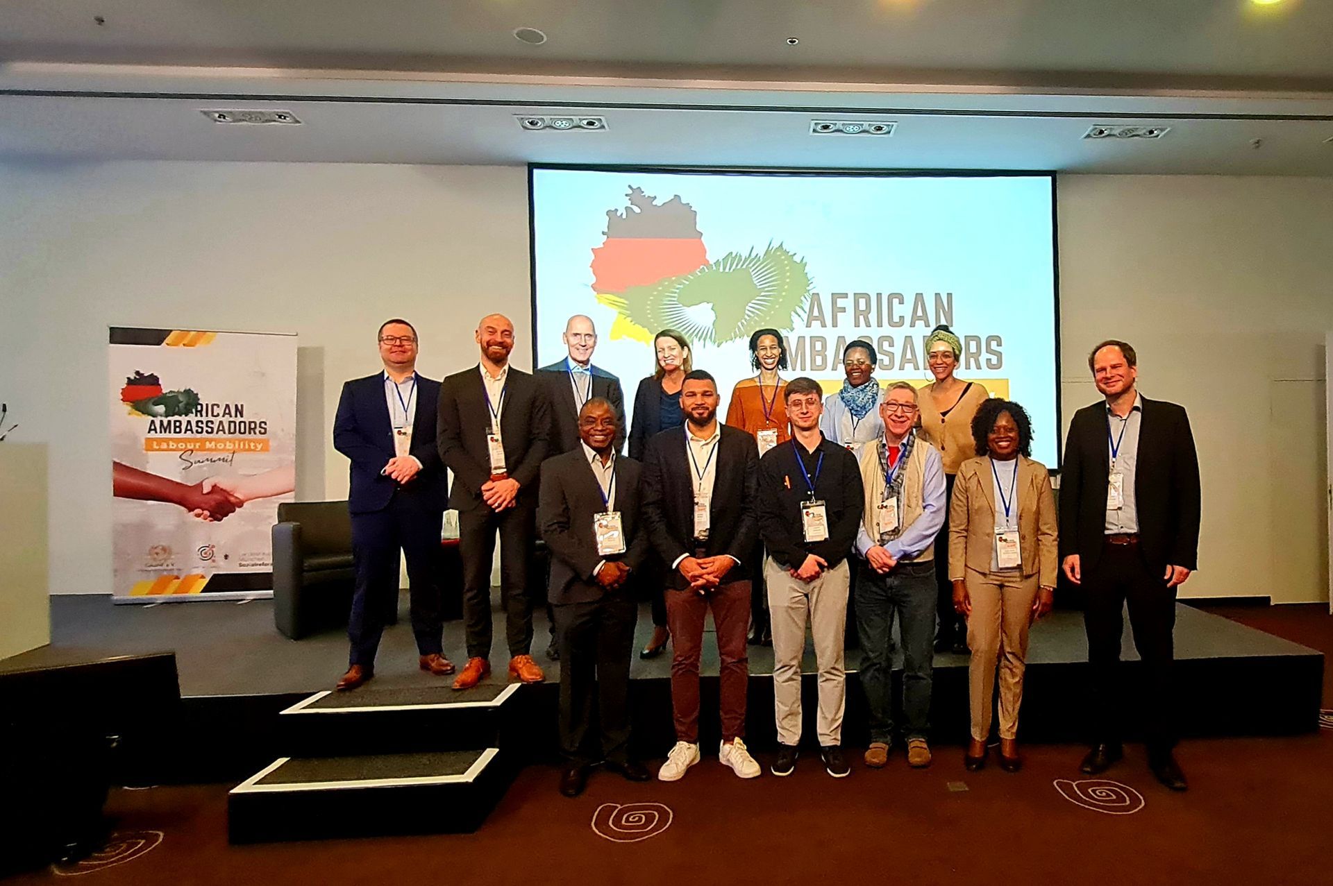 A group of people are posing for a picture in front of a large screen.