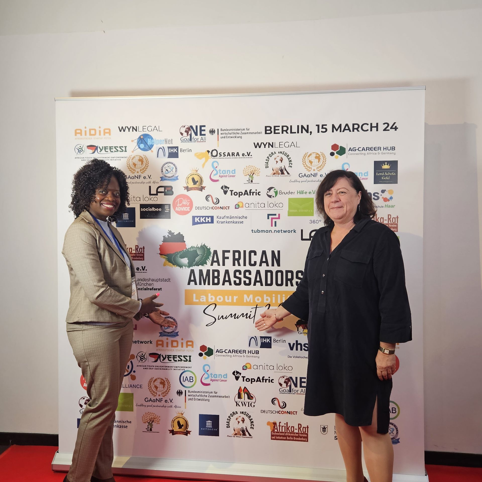 Two women standing in front of a wall that says african ambassadors