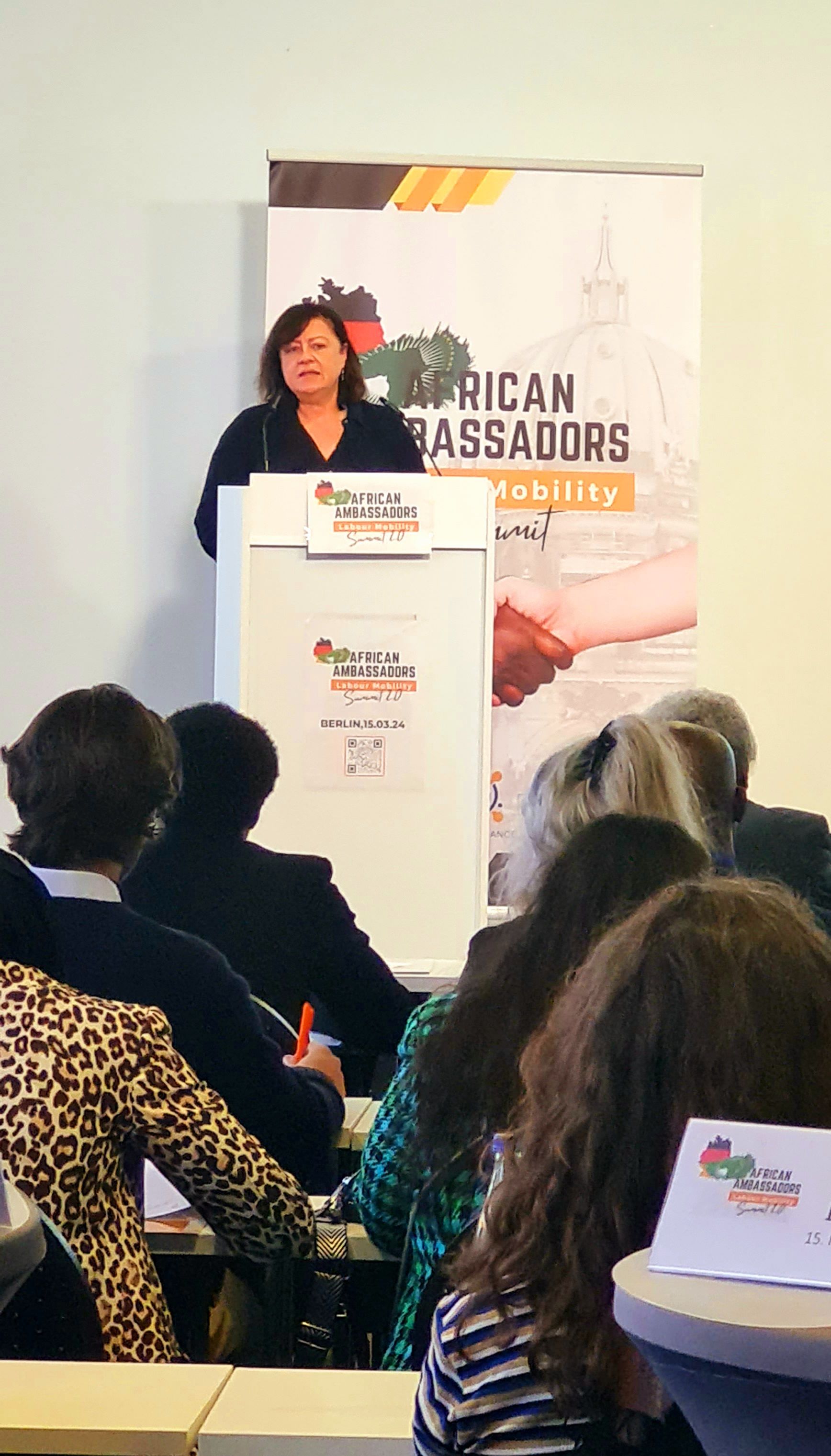A woman is standing at a podium giving a presentation to a group of people.