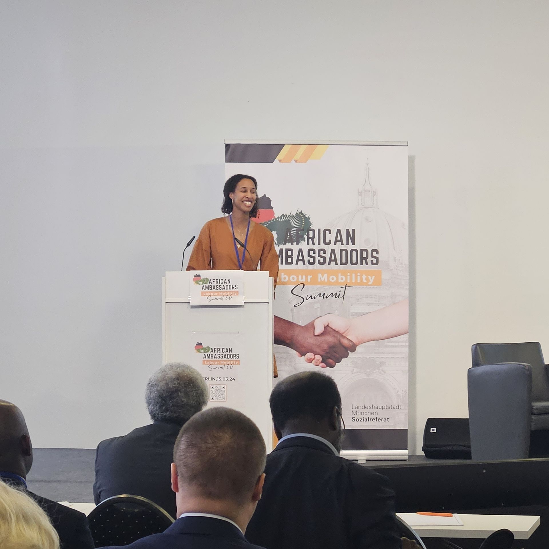A woman stands at a podium in front of a sign that says african ambassadors