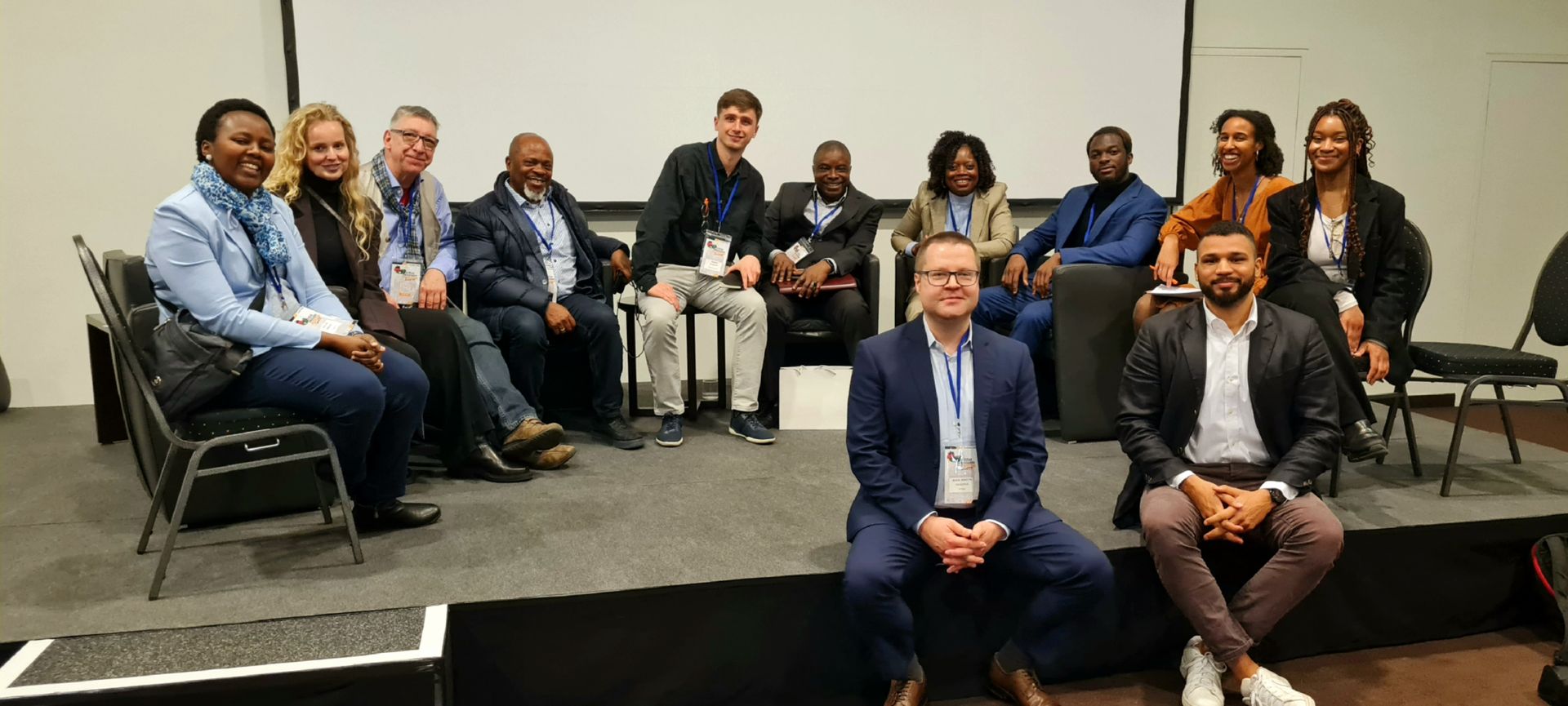 A group of people are sitting on a stage posing for a picture.