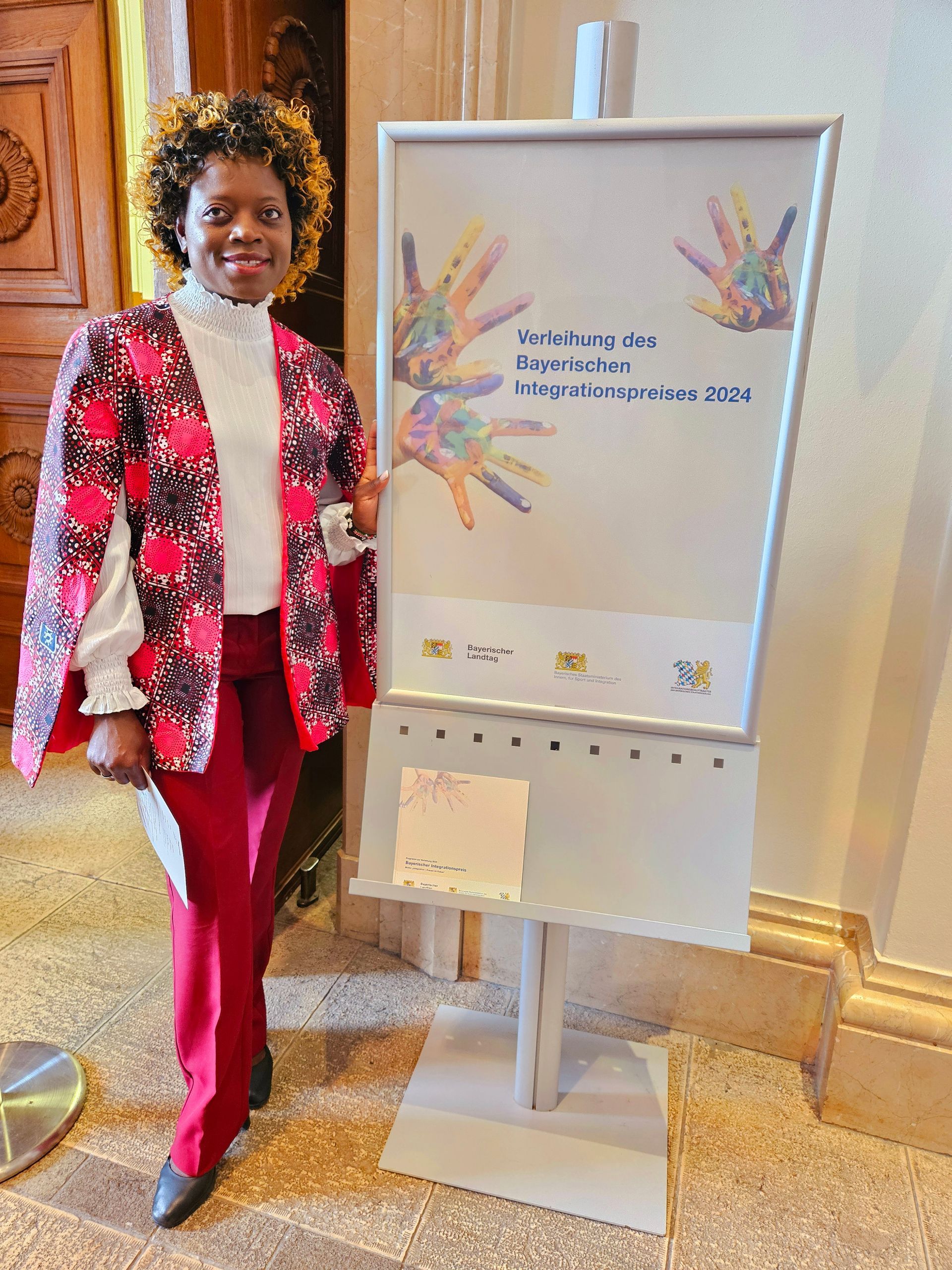 A woman in a red jacket is standing in front of a sign with hands on it.