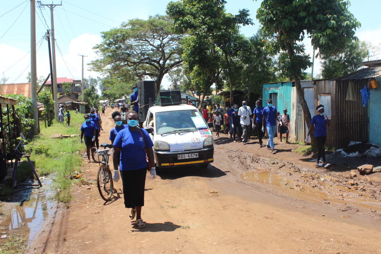 A group of people wearing masks are walking down a dirt road.