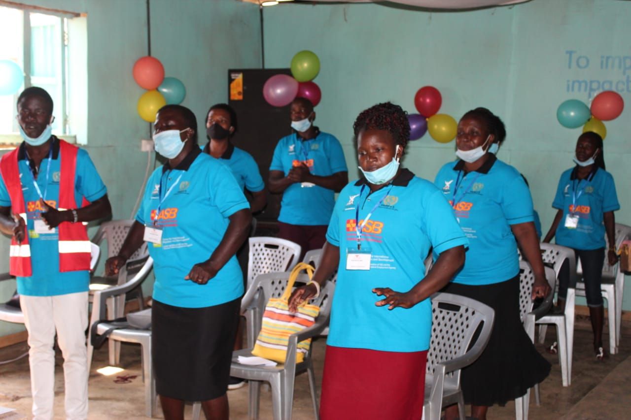 A group of people wearing face masks are standing in a room with balloons