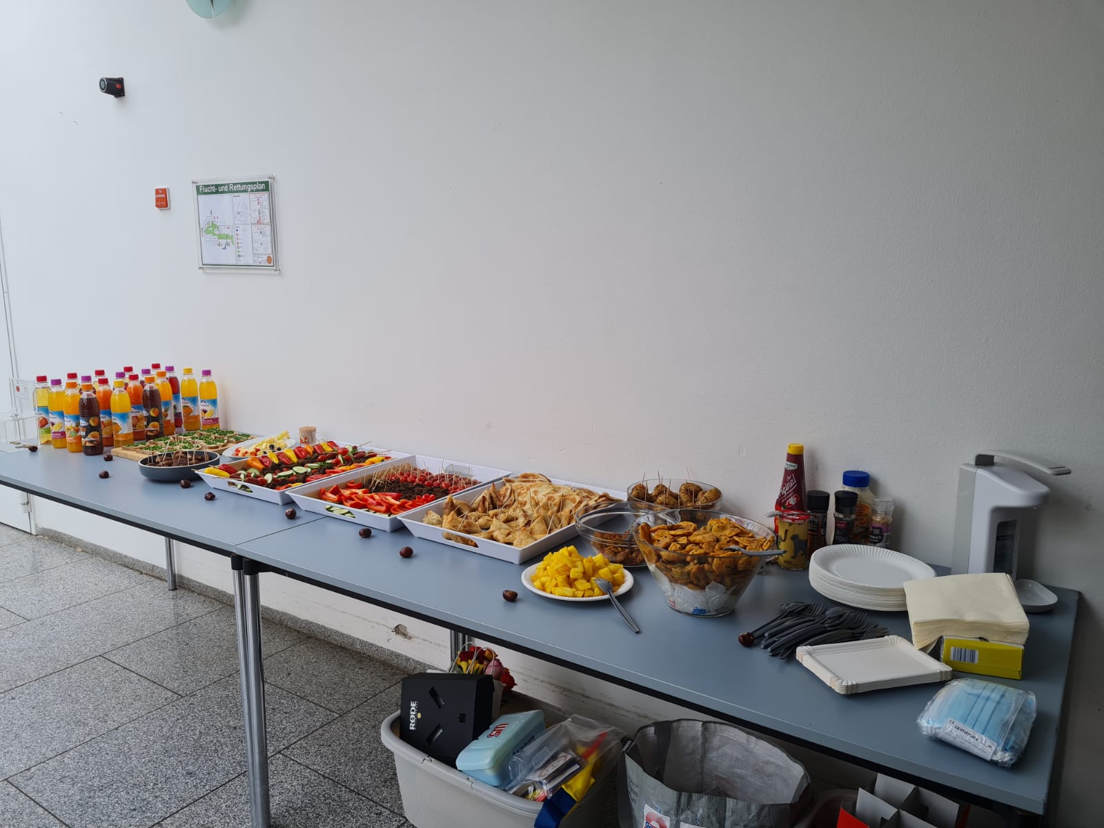 A long table with a variety of food and drinks on it.