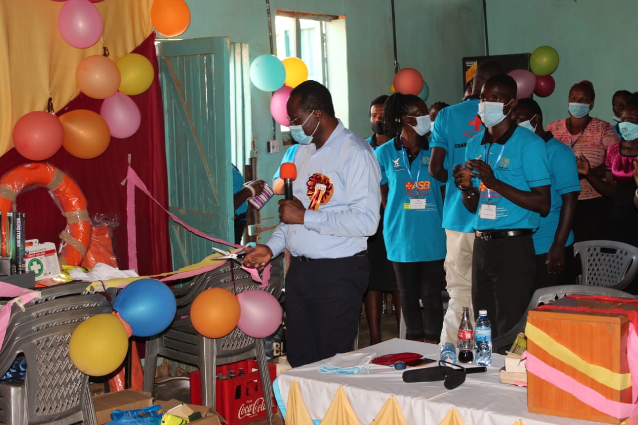 A group of people wearing face masks are standing around a table with balloons.