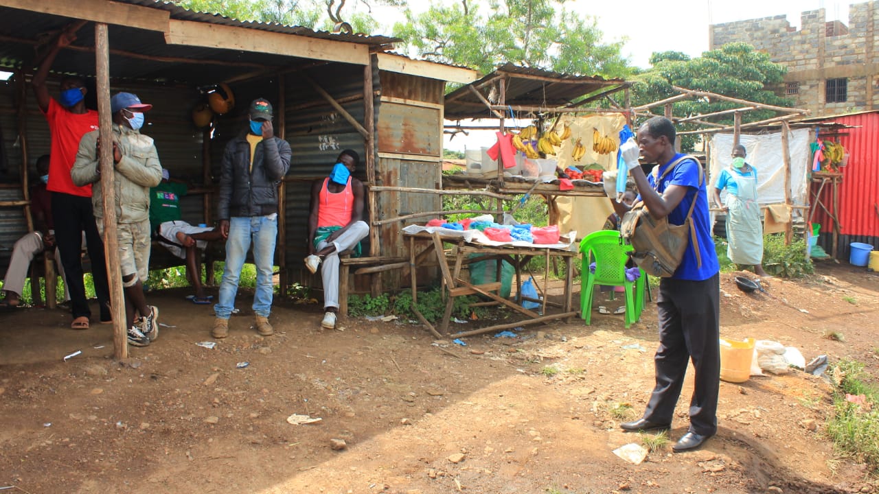 A man is standing in front of a group of people wearing masks.