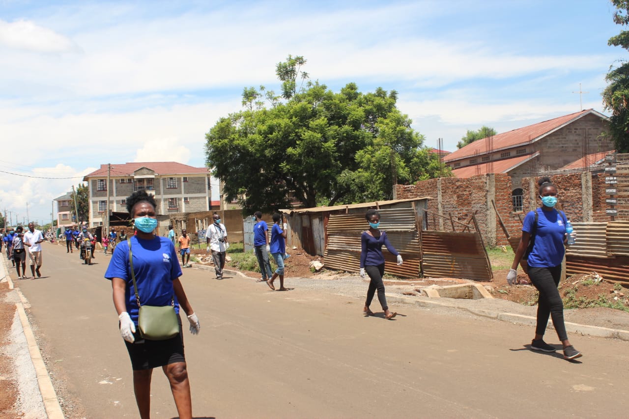 A group of people wearing masks and gloves are walking down a street.