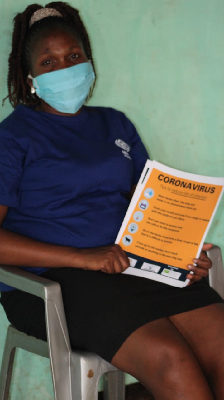 A woman wearing a mask is sitting in a chair holding a book titled coronavirus