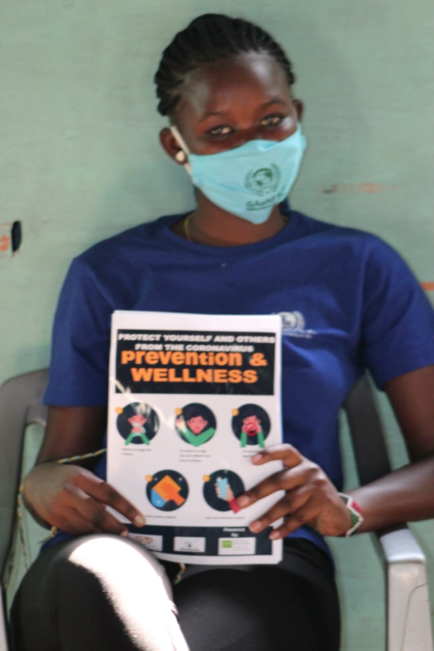 A woman wearing a mask is holding a pamphlet about prevention and wellness