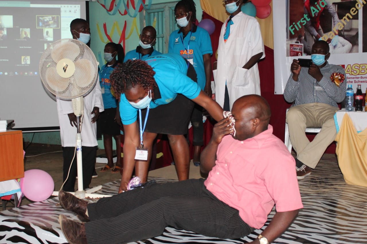 A man in a pink shirt is being helped by a woman in a blue shirt