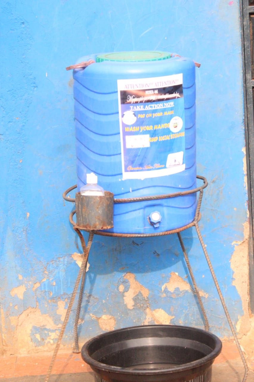 A blue barrel with a green lid is sitting on a metal stand next to a black bowl of water