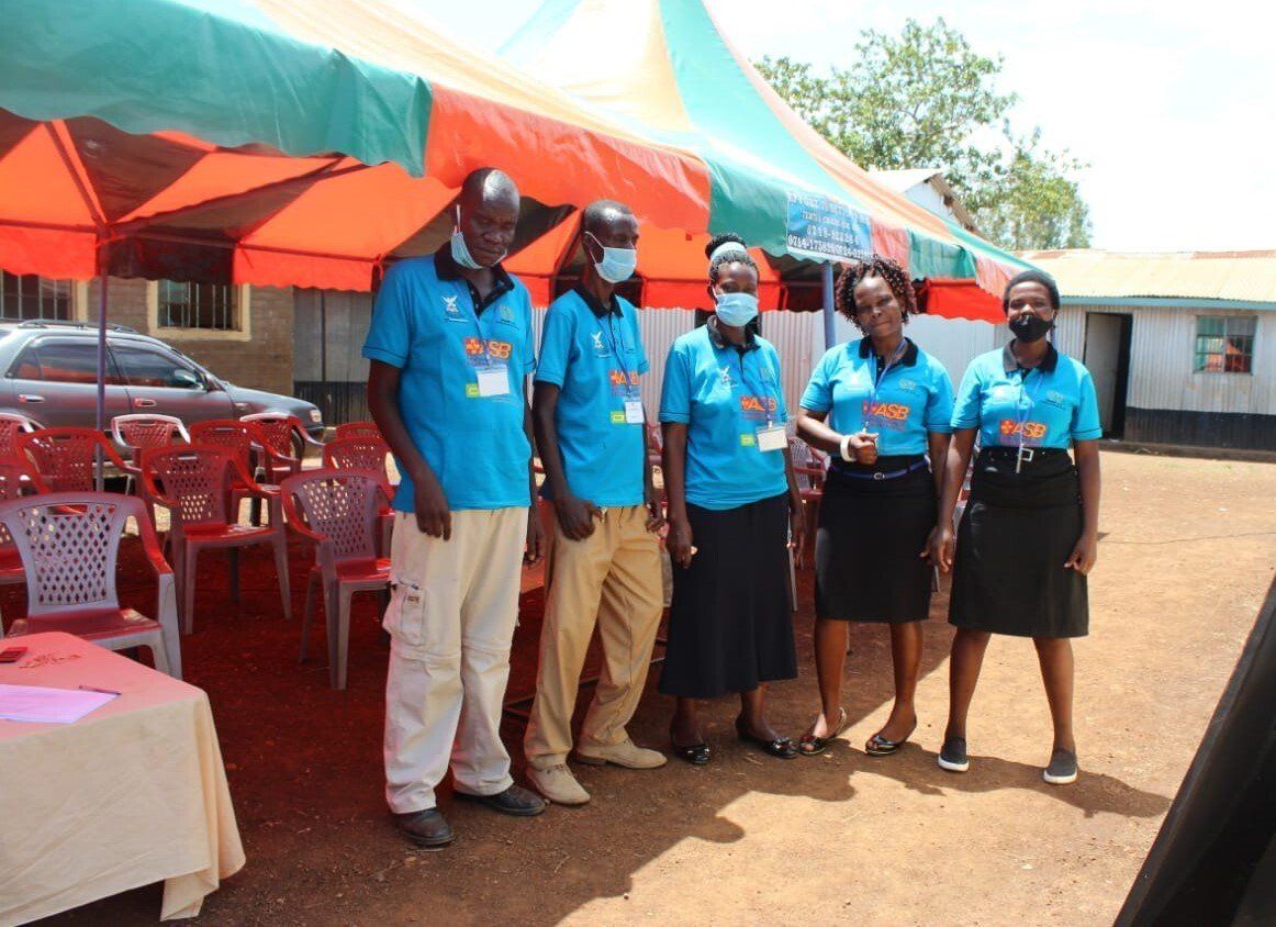 A group of people standing under a tent wearing masks