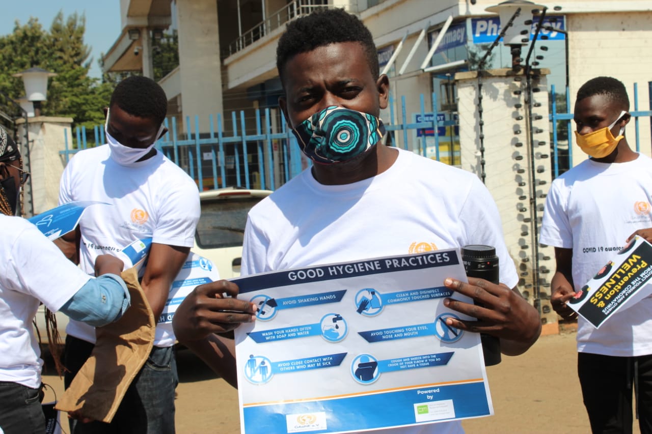 A man wearing a mask is holding a sign that says good hygiene practices