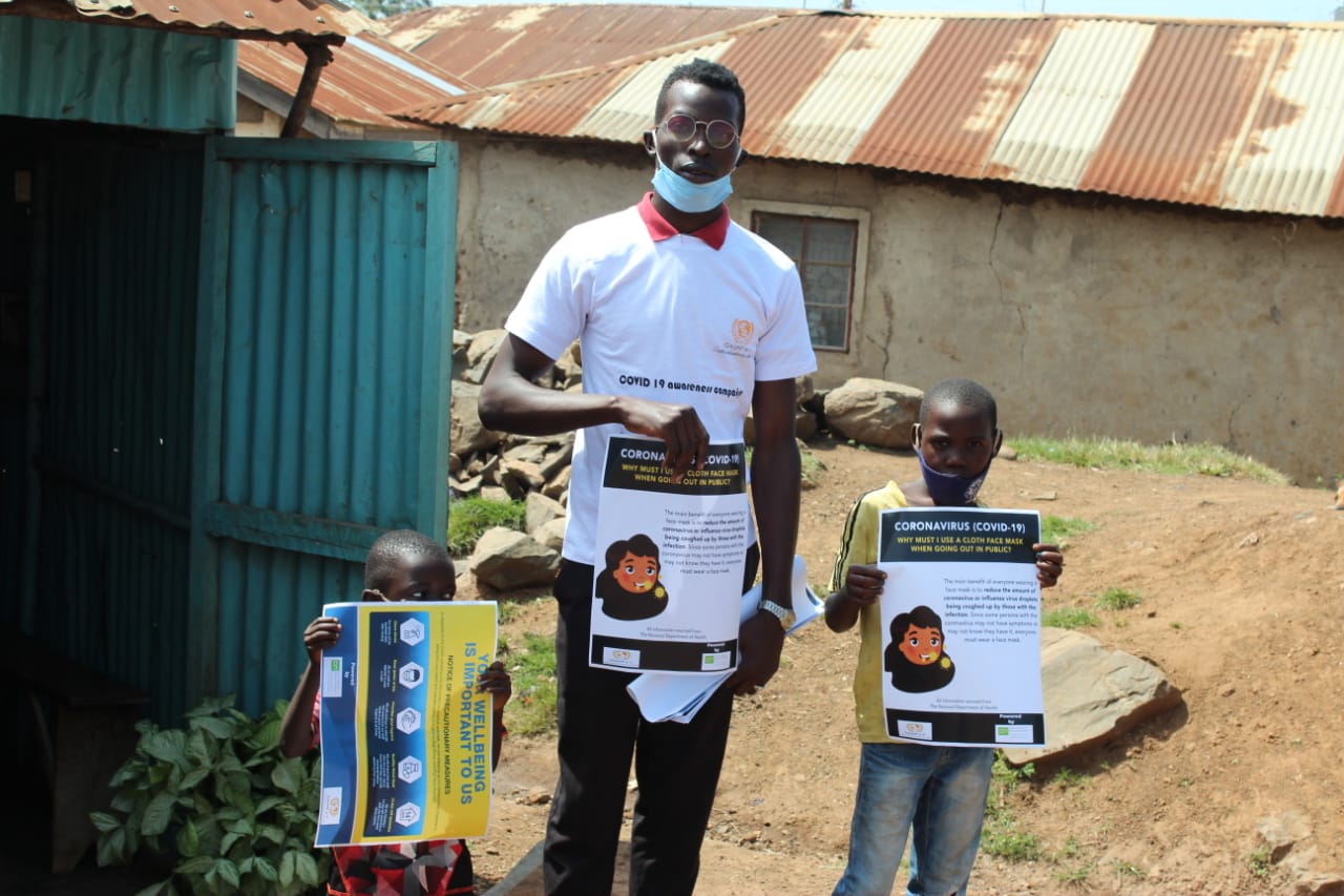 A man and two children are holding signs in front of a building.