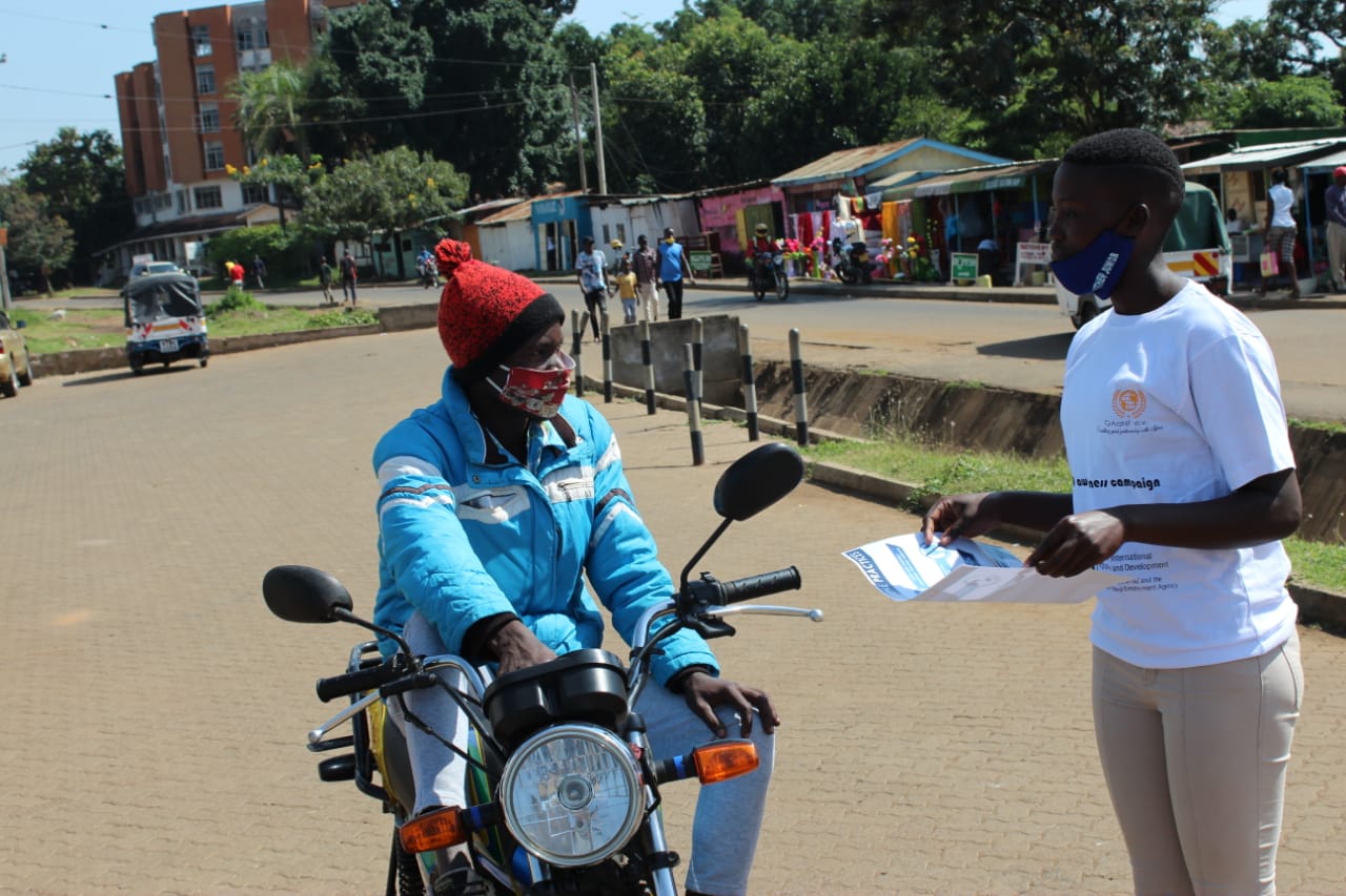 A man on a motorcycle is talking to a woman wearing a mask