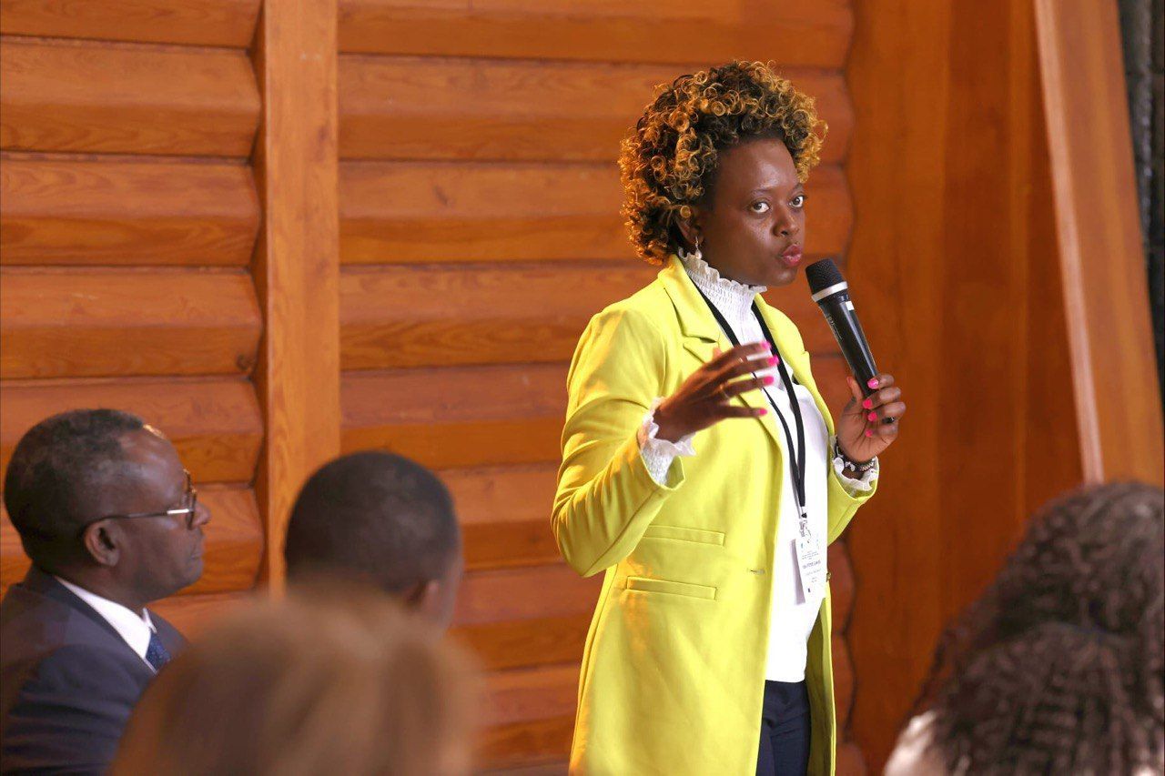 A woman in a yellow jacket is holding a microphone in front of a group of people.
