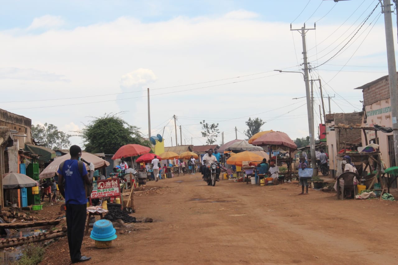A man in a blue shirt is standing in the middle of a dirt road.