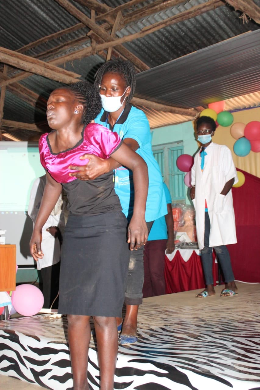 A woman wearing a mask is carrying another woman on her back