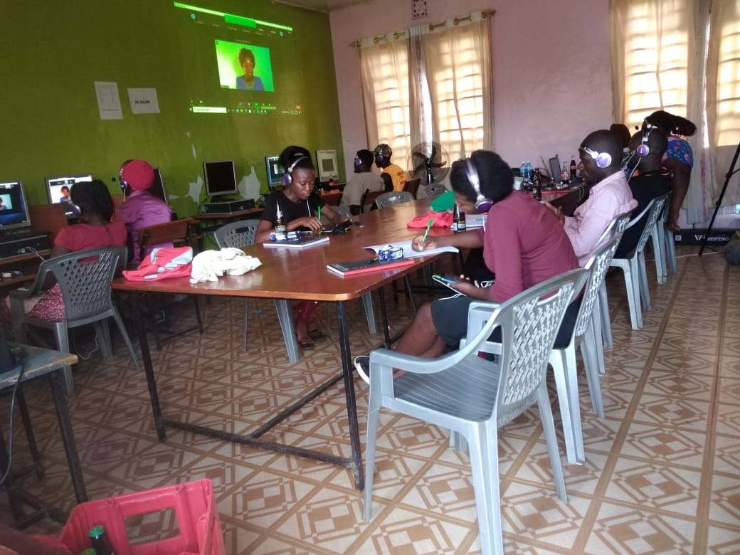 A group of people are sitting at tables in a room with headphones on.