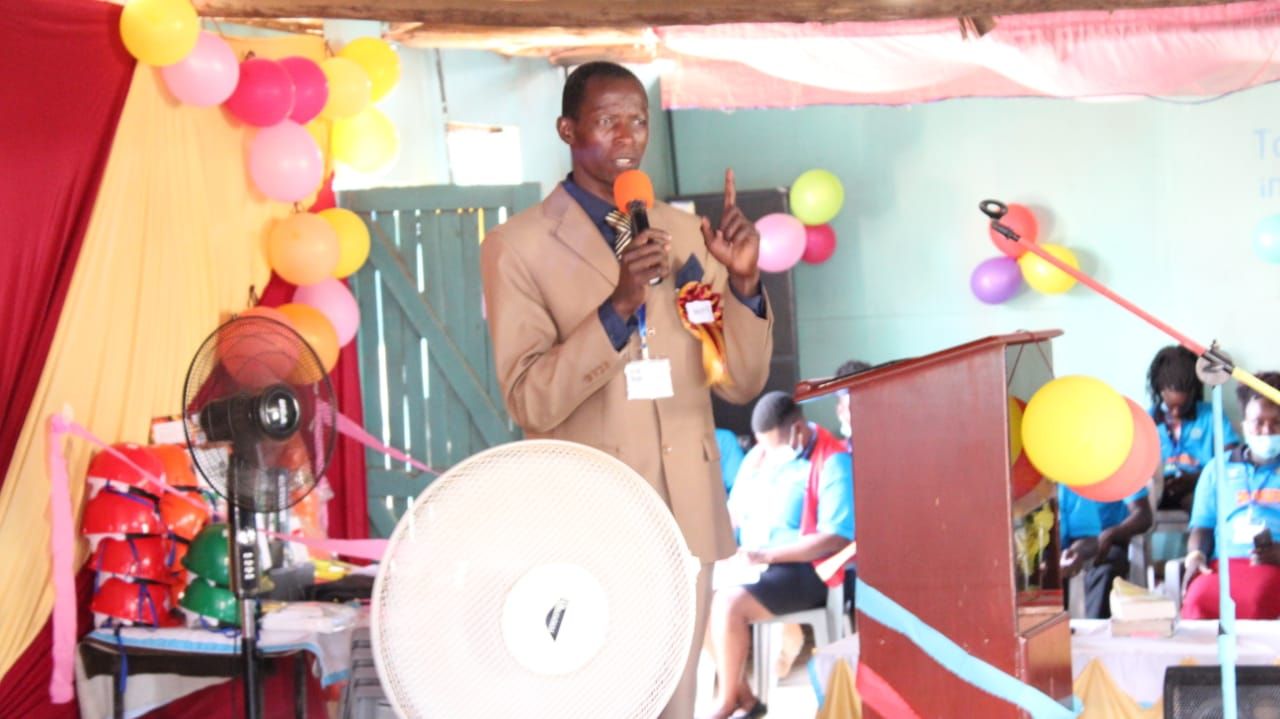 A man is speaking into a microphone in a room with balloons