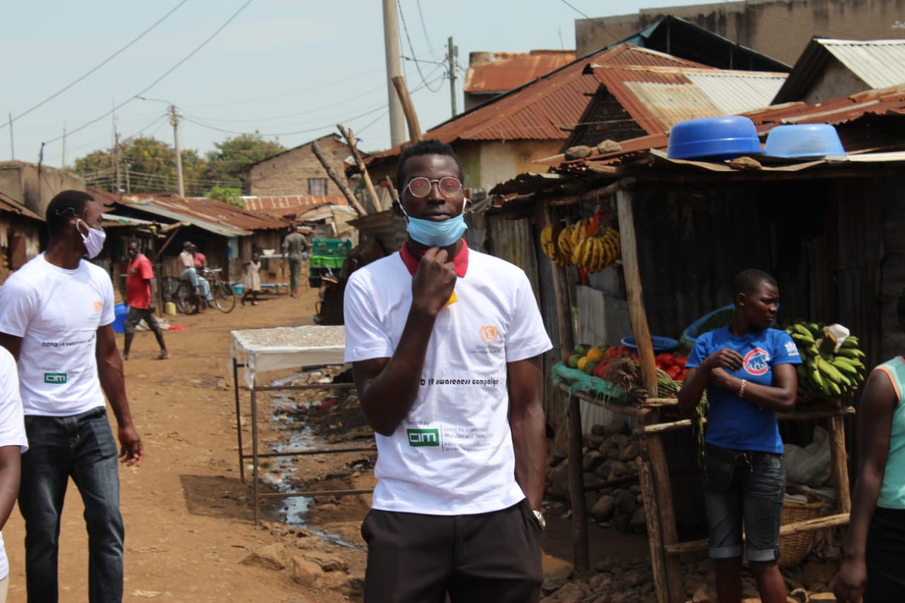 A man wearing a mask is standing in front of a fruit stand.