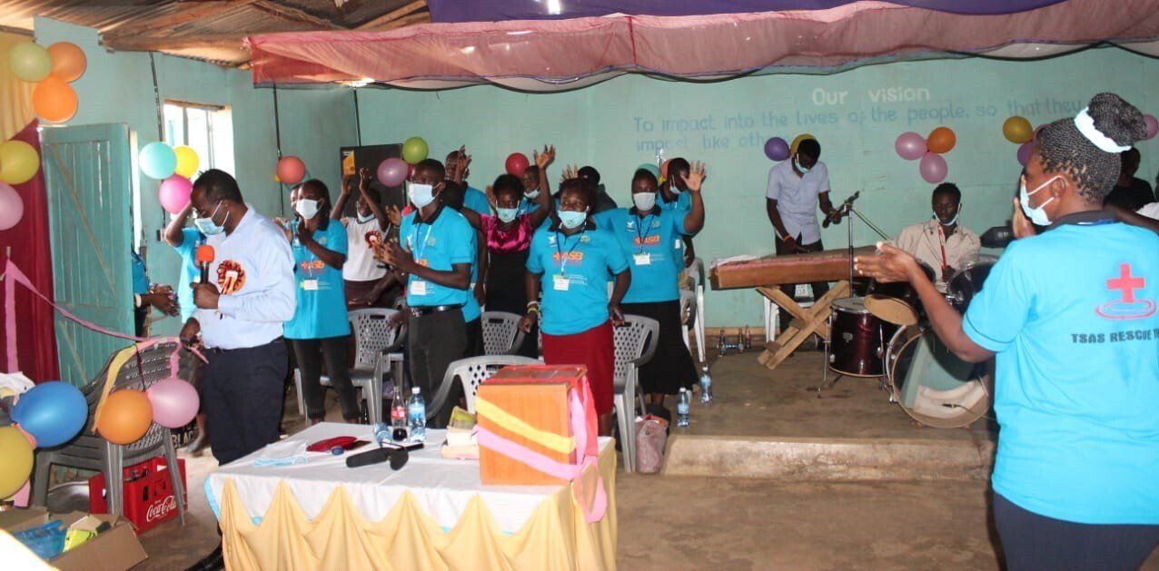 A group of people wearing face masks are standing in a room with balloons.