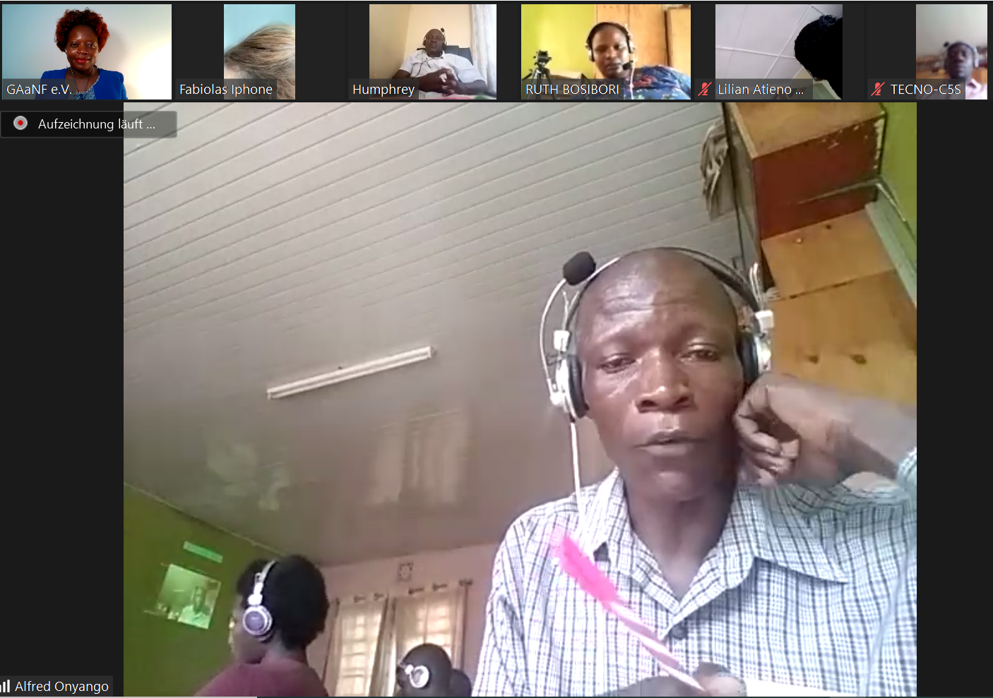 A man wearing headphones is sitting in front of a group of people on a video call.