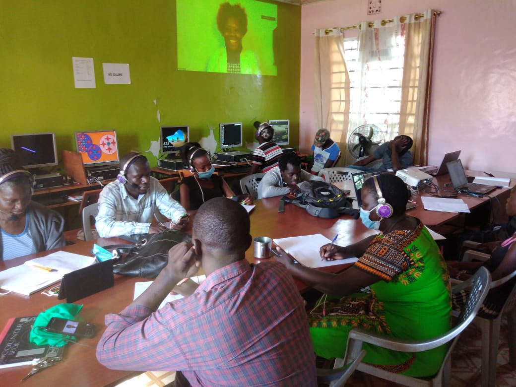 A group of people are sitting around a table in front of computers