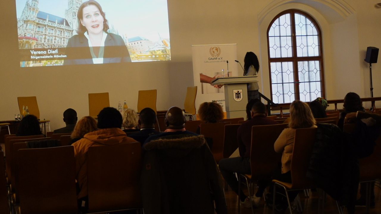 A group of people are sitting in chairs in front of a projector screen.