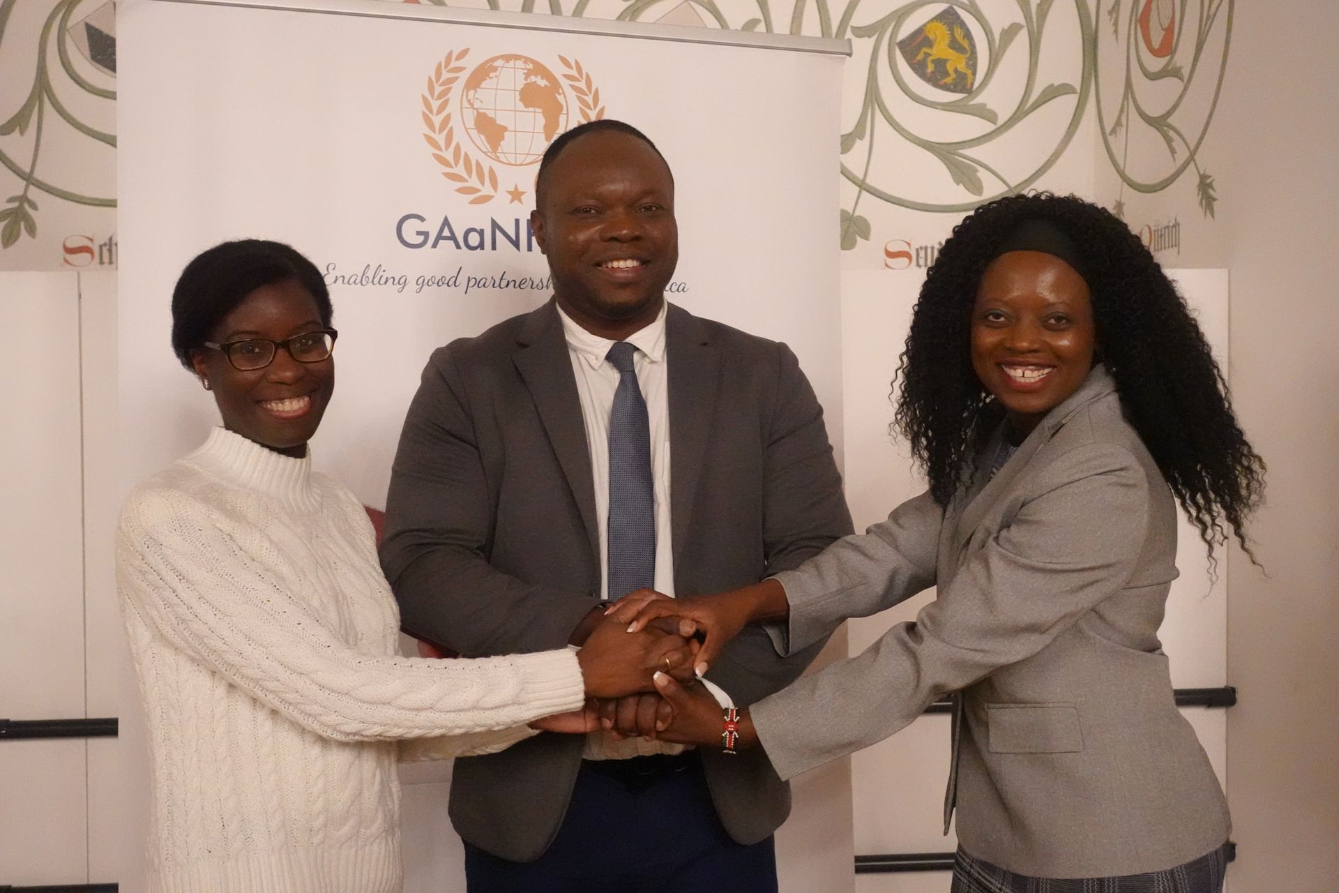 A man in a suit and tie is shaking hands with two women