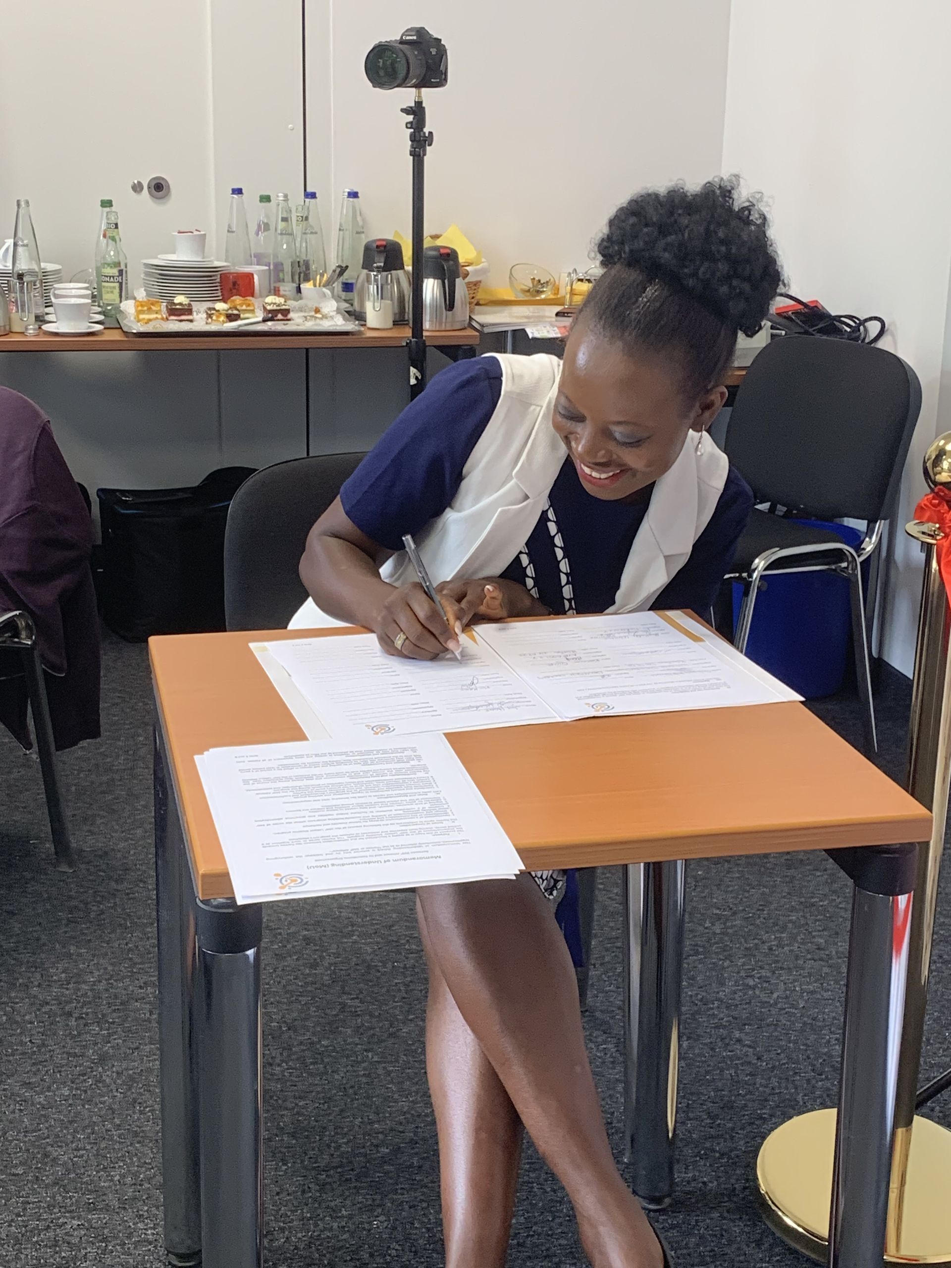 A woman is sitting at a table writing on a piece of paper