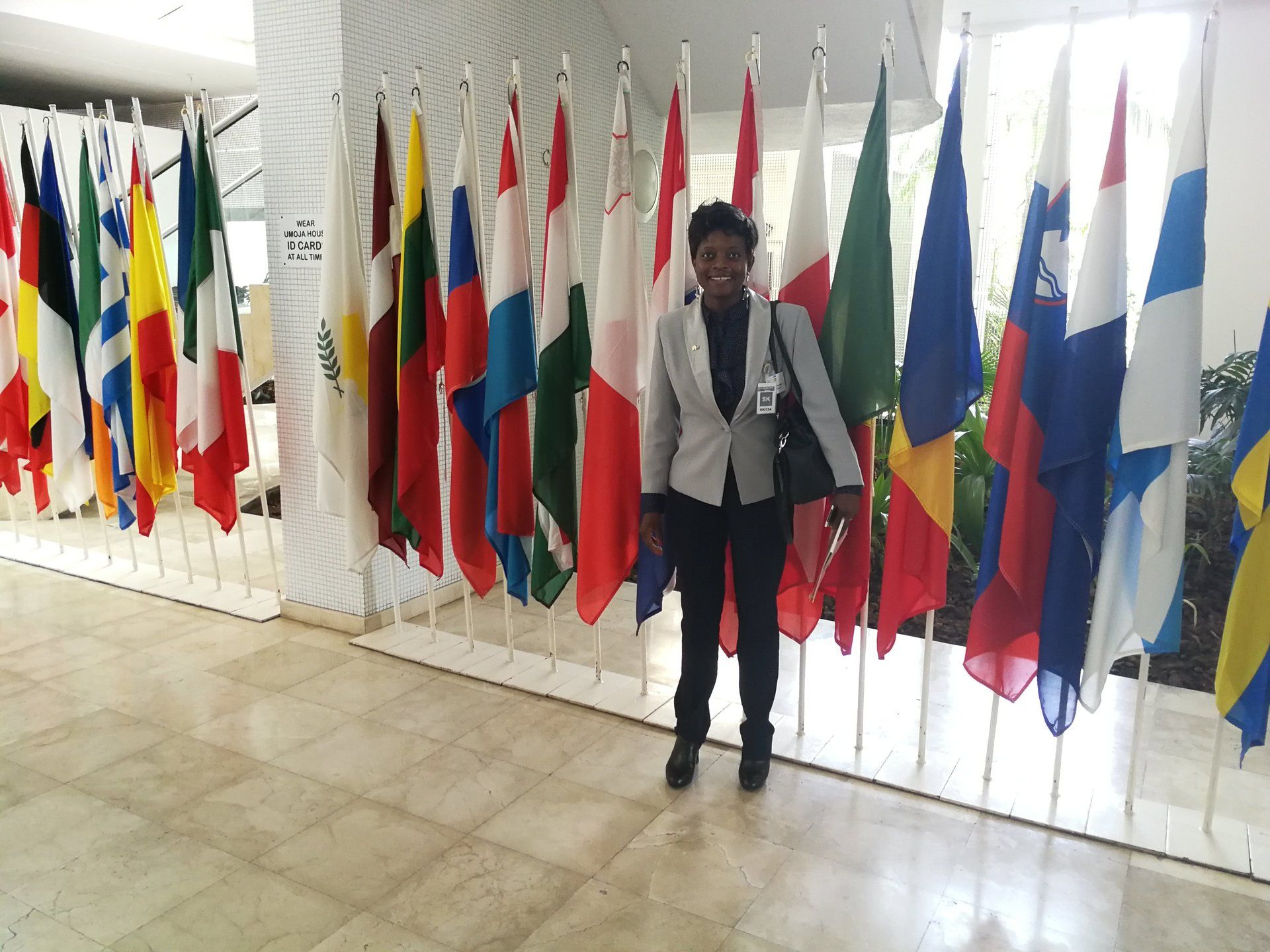 A woman is standing in front of a row of flags