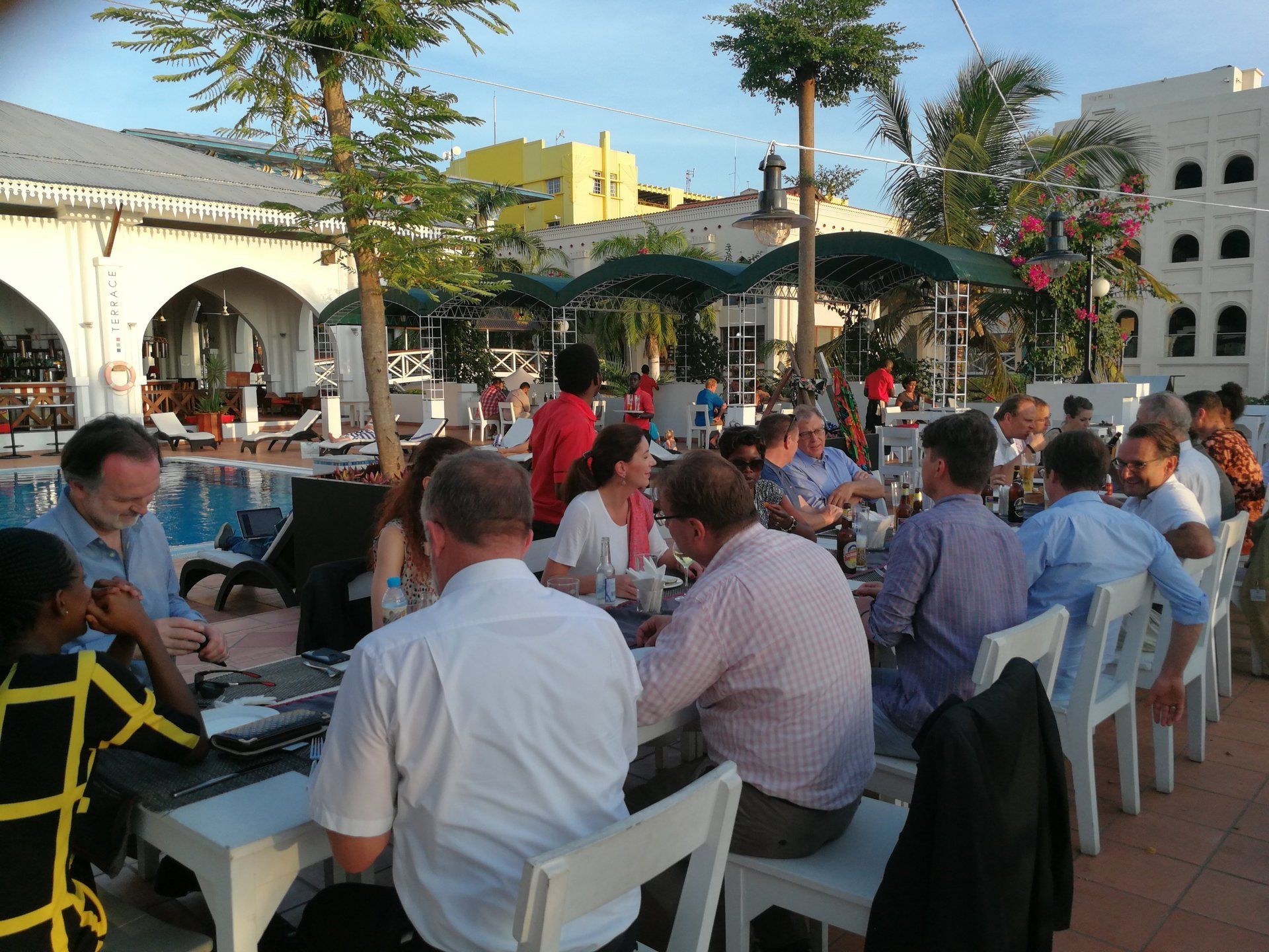 A group of people are sitting at tables in front of a pool
