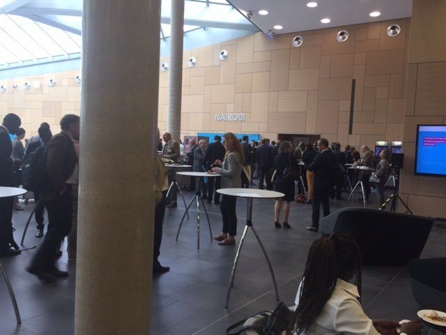 A group of people are gathered in a room with tables and a tv