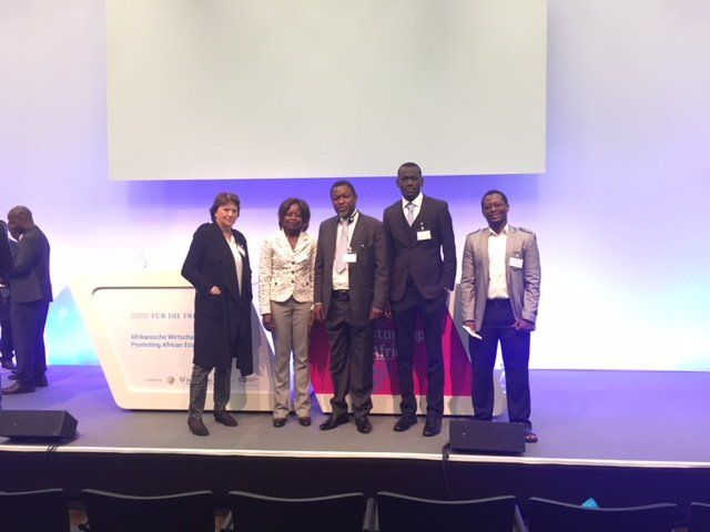 A group of people standing on a stage in front of a large screen