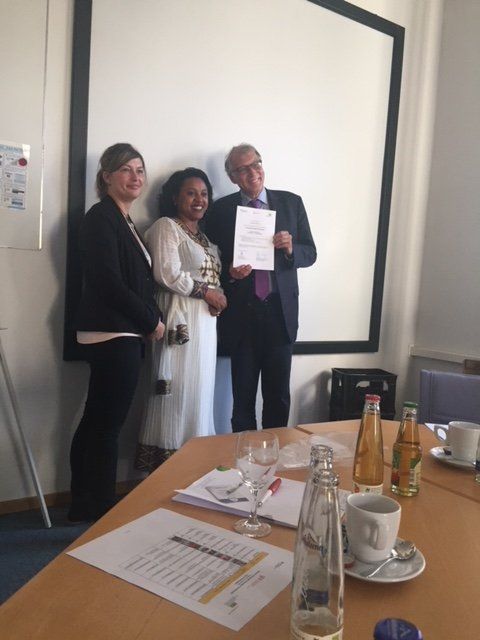 A group of people standing around a table with a man holding a certificate