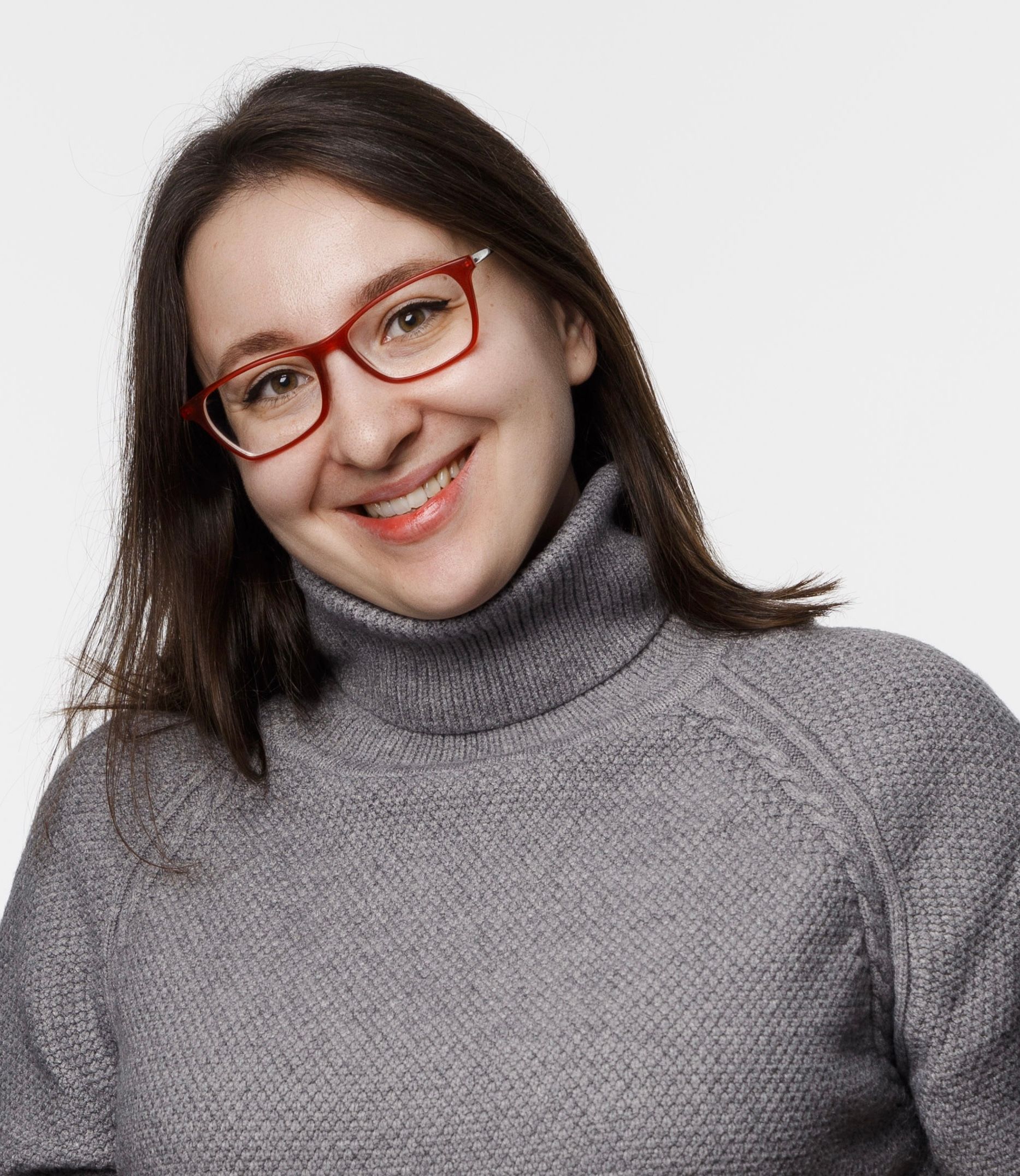 Eine Frau mit Brille und Rollkragenpullover lächelt.